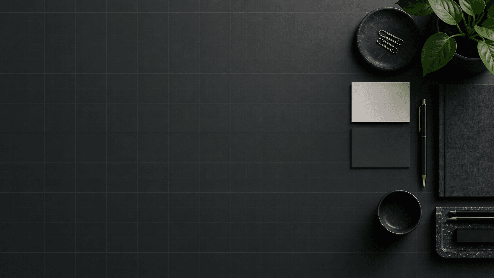 A dark project-planning surface with a subtle grid and neatly arranged desk materials